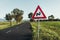 Photo of illuminated and warning road sign - double curve next to the road on meadow. Double Bend warning road sign on country