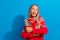 Photo of impressed schoolgirl with blond hair dressed sweater look at promo empty space hug gift isolated on blue color