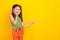 Photo of impressed small tails hairdo girl index empty space wear green top orange trousers isolated on yellow