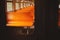 A photo of the interior of an empty retro train with orange seats, taken through the glass of the door. Commuter train travel