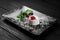 Photo of italian panna cotta dessert with strawberry sirup and mint leaf on the black wooden background.