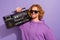 Photo of joyful beard orange hairdo guy listen boombox wear sunglass hoodie isolated on purple background