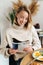 Photo of joyful blonde woman reading magazine while having breakfast