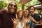 Photo of joyful hippie people men and women, taking selfie in forest near retro minivan