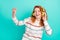Photo of joyful orange wavy hairstyle young lady dance listen music wear headphones white sweater isolated on teal color