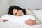 Photo of joyful woman 30s smiling, while lying in bed with white linen at home