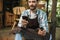 Photo of joyous waiter man using smartphone while working in cafe or coffeehouse outdoor