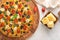 In the photo in the left corner, we see pizza on a beautiful wooden stand. On the right in the photo, in a wooden bowl, cheese,