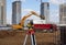 Photo of a level at the construction site of multi-storey buildings with a yellow excavator and an red truck on the street in the