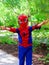 Photo of a little boy in a spiderman costume and mask outdoors on a spring sunny day