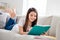 Photo of little pretty pupil school lady lying comfy sofa reading diary book positive good mood diligent student write