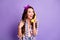 Photo of lovely excited girl hold wired phone listen look empty space wear plaid shirt vintage headband isolated purple