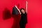 Photo of lucky cheerful curly woman wear casual black outfit holding bags arms up isolated red color background