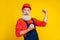 Photo of lucky cheerful senior guy dressed uniform overall red hardhat rising fists smiling isolated yellow color