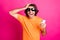 Photo of man hand head hold telephone open mouth wear orange t-shirt sunglass isolated pink color background