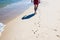 Photo of man walking on the hot sandy beach leaving footsteps next to the dog`s footprints