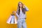 Photo of mature charming positive grandma shopaholic visit big mall buy clothes isolated on yellow color background