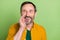 Photo of mature man happy positive smile hands near mouth advertisement speak look empty space isolated over green color