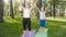 Photo of middle aged woman teaching her student in yoga class at park. Woamn with teenage boy practising fitness