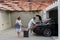 A photo of a modern family carrying suitcases from a garage to their luxury seaside home during a vacation. Vacation