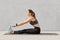Photo of motivated girl does stretching workout or acrobatics exercises on fitness mat, recieves yoga lesson, has dark hair combed