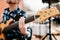 Photo of musician playng on six string fretless bass guitar on the street in front of people.