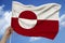 Photo of the national flag of Greenland on a luxurious texture of satin, silk with waves, folds and highlights, close-up, copy