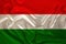 Photo of the national flag of Hungary on a luxurious texture of satin, silk with waves, folds and highlights, close-up, copy space