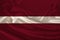 Photo of the national flag of Latvia on a luxurious texture of satin, silk with waves, folds and highlights, close-up, copy space