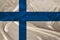 Photo of the national flag of the state of Finland on a luxurious texture of satin, silk with waves, folds and highlights, close-