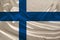 Photo of the national flag of the state of Finland on a luxurious texture of satin, silk with waves, folds and highlights, close-