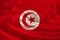 Photo of the national flag of Tunisia on a luxurious texture of satin, silk with waves, folds and highlights, close-up, copy space