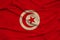 Photo of the national flag of Tunisia on a luxurious texture of satin, silk with waves, folds and highlights, close-up, copy space