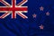 Photo of the New Zealand state national flag on a luxurious texture of satin, silk with waves, folds and highlights, close-up,