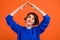 Photo of nice brunette short hairdo young lady look hands roof wear blue sweater isolated on orange color background