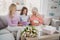 Photo of nice happy family retired pensioner women sit sofa 8-march smile present flowers cards indoors inside house