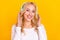 Photo of nice millennial blond lady listen music wear headphones shirt jeans isolated on yellow background