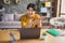 Photo of office worker guy sit desk explain idea count fingers video conference wear yellow shirt home indoors