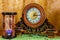 Photo of an old clock and sandglass on brown background