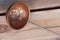 Photo of an old fashioned copper ladle lying on wooden planks