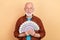 Photo of old grandpa in spectacles hold lots of money win lottery become millionaire isolated on beige color background