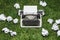 Photo of old typewriter on a green grass with a sheet of paper.