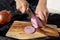 Photo of the onion slicing process. A woman cuts onions into circles with a knife