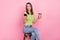 Photo of optimistic brunette millennial lady coffee break pause look telephone wear green t-shirt isolated on pink color