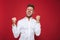 Photo of optimistic man in formal wear shouting and clenching fists, isolated over red background