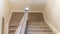 Photo Panorama U shaped staircase with handrails and gray carpet inside a home with white wall