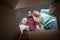 Photo of parents and daughter looking inside cardboard box