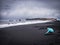 Photo of a person kneeling on a beautiful beach in Iceland, enjoying the mesmerizing view of the ocean