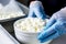 Photo of a person preparing cottage cheese in a bowl with gloves on. Preparation of cottage cheese for cheese production. Handmade