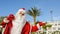 Photo pf santa claus walking near a resort on the seaside near palm trees